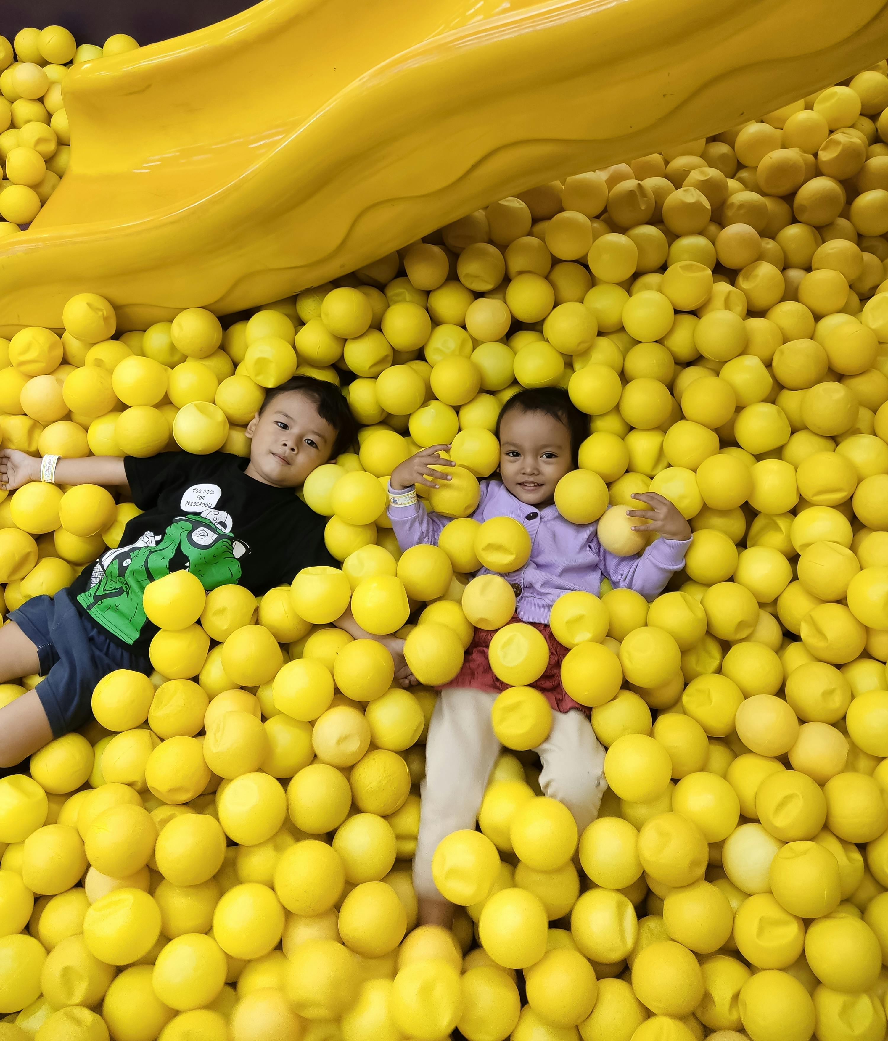 Kids having fun in a yellow ball pit in Subang, Indonesia, enjoying playful moments.
